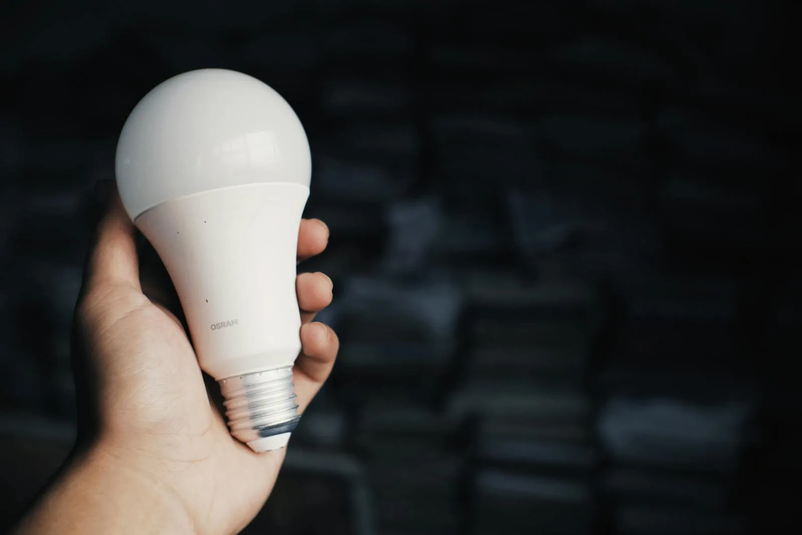 Hand holding a smart LED bulb ready for installation in a connected home