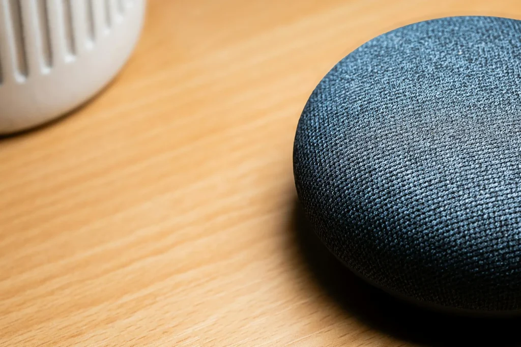 Smart speaker sitting on a kitchen counter next to a coffee mug